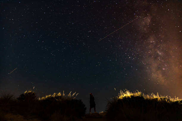 istock Woman under night sky with stars on sand dunes. 1170095365