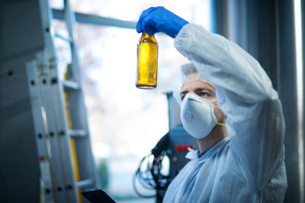 technologen-experte in der bierproduktionsfabrik, die glasflasche hält und die qualität überprüft. lebensmittel- und getränkequalitätskontrolle. - mint liquor stock-fotos und bilder