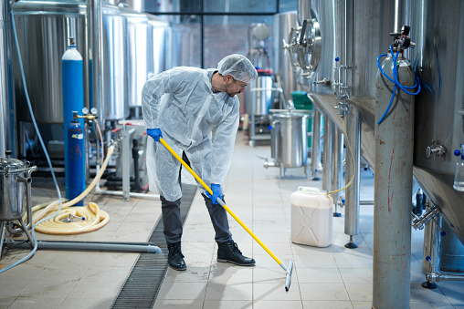 Limpiador industrial profesional en suelo de limpieza uniforme protector de la planta de procesamiento de alimentos. Servicios de limpieza. photo