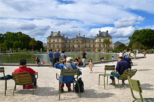 Paris, France-06 19 2019:People resting nearby the pond of the Luxembourg garden in Paris.The Luxembourg Palace was originally built to be the royal residence.Since 1958 it has been the seat of the French Senate,the upper house of the French Parliament,In front of the building lies the Senate's garden, the Jardin du Luxembourg, open to the public.