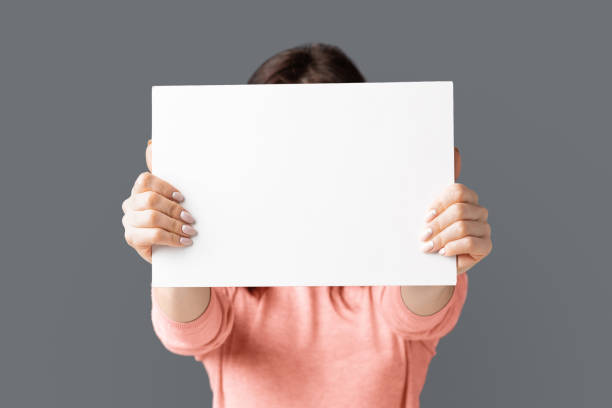 istock Woman holding empty advertising board in front of her face 1170099347