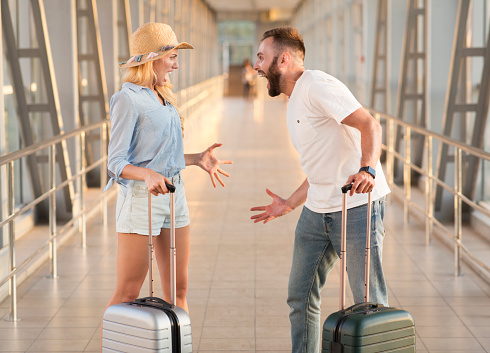 Couple arguing at airport terminal, forgot some things at home, side view