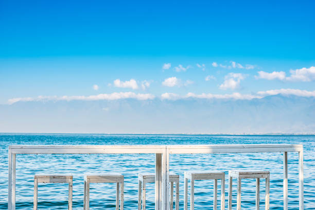 White table and chairs against the blue lake. Located in Erhai Lake, Dali, Yunnan, China.