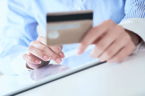 istock Close-up woman's hands holding a credit card and using tablet pc for online shopping. Middle section of young businesswoman making online payments with credit card and tablet. 1170102252