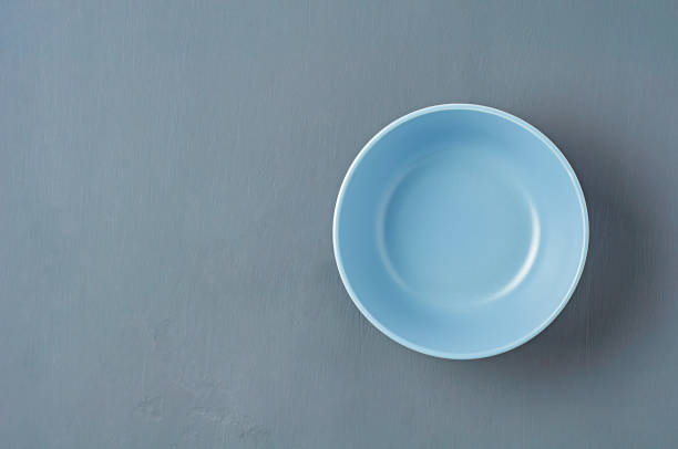 istock Deep empty ceramic bowl of blue color lies on dark concrete background. Space for text. Top view 1170109775