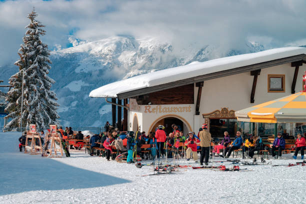 People relaxing at restaurant at Zillertal Arena in Austria Rohrberg, Austria - February 4, 2019: People relaxing at restaurant and cafe under clouds on Zillertal Arena ski resort in Tyrol, Mayrhofen in Austria in winter Alps. Ski and snowboards on background winter village austria tirol stock pictures, royalty-free photos & images