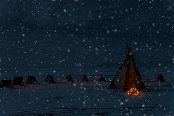 istock Winter snowfall and camping tent with bonfire, night light photo, monotone image 1170120802