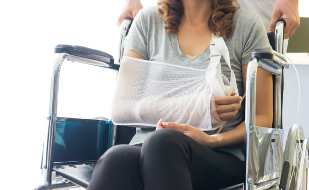 Broken arm Asian woman with arm sling sponsored in her hands sitting on a wheelchair Ideas for accident Injuries and health care. stock photo