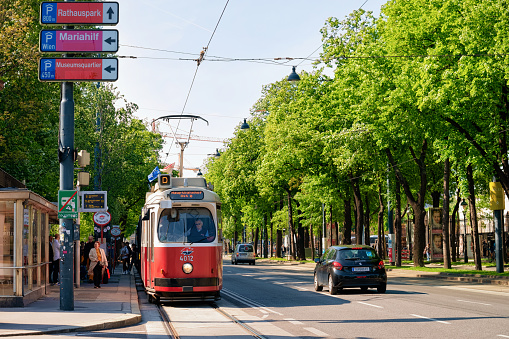 Vienna, Austria - May 8, 2019: Red tram on road between Museumstrasse of MuseumsQuartier and Mariahilfer Strasse in Innere Stadt of Old city center in Vienna in Austria. Street with traffic in Wien