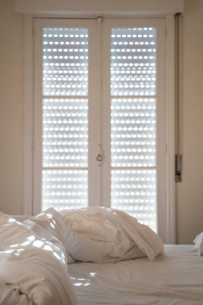 istock White pillow on white bed with morning sunlight. Vertical view. 1170131331