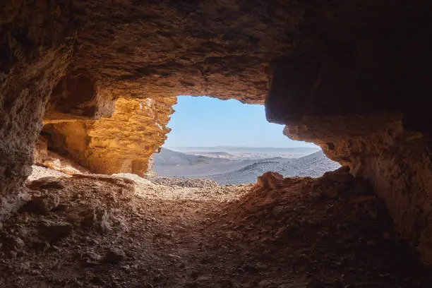 Photo of View from the inside of a cave to the rocky desert in the Sahara in Sudan lying under a glistening sun.