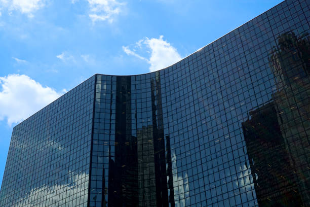 enorme silhouette di un edificio per uffici moderno nero su uno sfondo di cielo blu con nuvole bianche. - high rise apartments foto e immagini stock