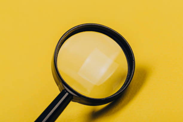 istock Small magnifying glass on yellow background, search symbol 1170144999