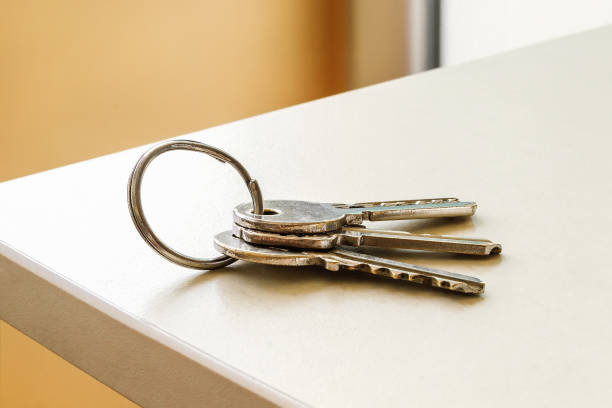 Set of three house keys on the ring on table in a room. Bunch of apartment keys close-up. To forget keys at home consept. stock photo