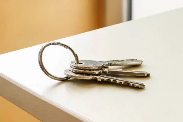 Set of three house keys on the ring on table in a room. Bunch of apartment keys close-up. To forget keys at home consept. Close-up.