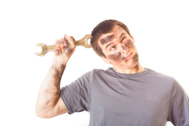 dirty and funny mechanic with wrench thinking isolated on white