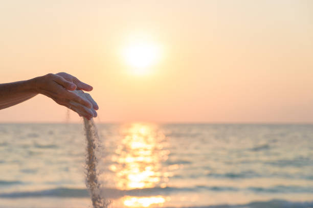 istock Woman dropping sand grains from hands  performing yoga exercise, romantic sky at sunset, side view, golden sunlight, real people 1170152679