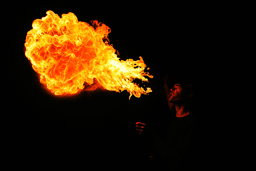 Hawaiian male dancer twirls torch with hands.
