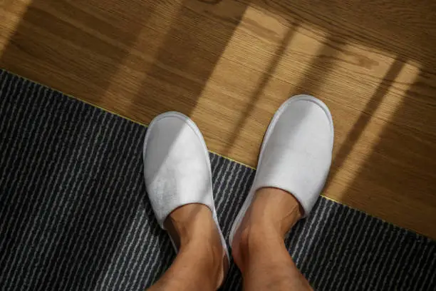 Photo of Male feet wearing white hotel slippers, view from above