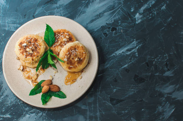 istock Cheesecakes,cottage cheese pancakes with almonds,fresh mint and maple syrup on a gray background from a concrete table copy space. Cheesecakes, homemade traditional Ukrainian and Russian cheesecakes 1170158694