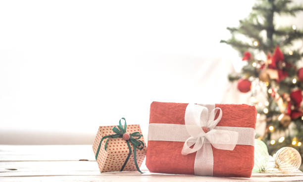 istock Red Christmas present over Christmas lights and Christmas tree on light background on cozy rug. Christmas decorations 1170168707
