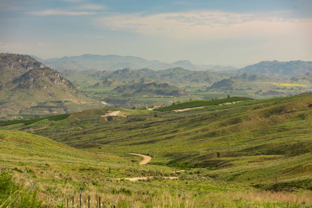 istock Country Road Runs Down Steep Valley Toward Distant Orchards. 1170172599