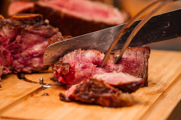 istock Slicing rare beef steak on a woodeng cutting board, close-up. 1170175756