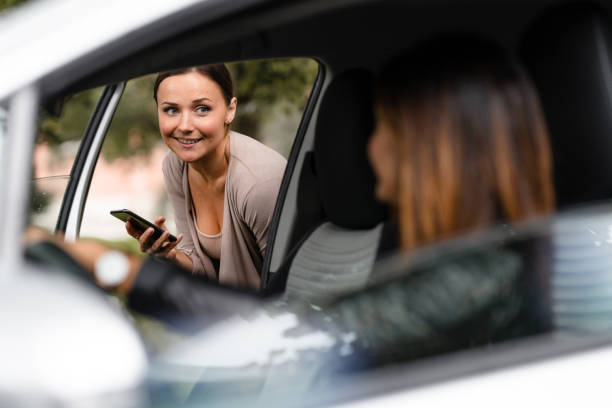 mujer pidiendo un taxi con su teléfono inteligente en un día lluvioso - car pooling fotografías e imágenes de stock