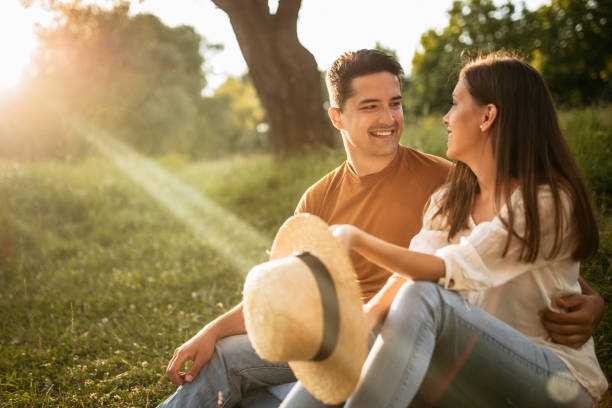 istock Young couple taking a break from walk on meadow in sunset 1170180221