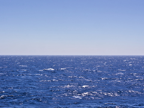 Wavy deep blue sea and sky. Horizon line in the middle of the frame.