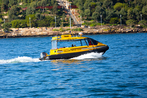 Sydney, Australia - July 07, 2019: Yellow water taxi with passengers traveling in Barangaroo Harbour. Yellow Water Taxis provide services for private charters, taxi transfer, harbour sightseeing and combo packages with Sydney iconic attractions.