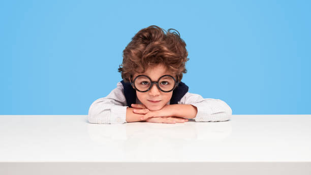 istock Nerdy schoolboy sitting at desk 1170192928
