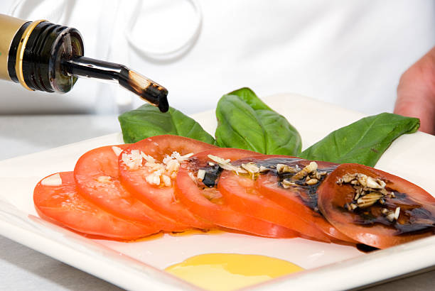 chef décorer une assiette avec tomatos basi et de l'huile d'olive - vinegar bottle herb white photos et images de collection