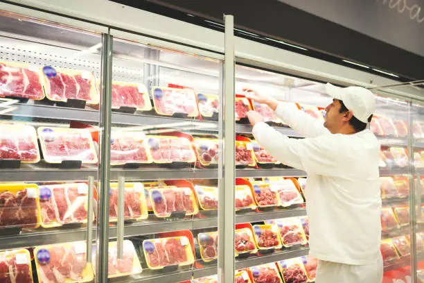 Photo of Worker in a supermarket handling meat