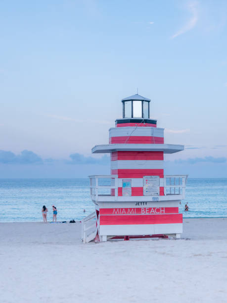 menschen, die es leicht in der nähe eines lifeguard tower seagull am südstrand bei sonnenuntergang - lifeguard orange nature beach stock-fotos und bilder