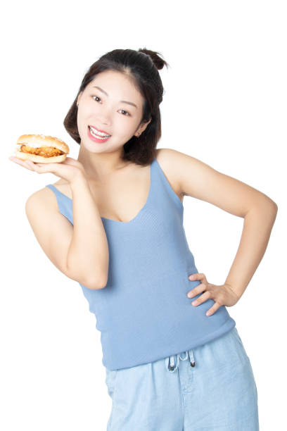 Chinese American woman eating Chicken Sandwich isolated on white background