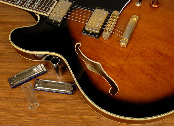 Close-up of an electric guitar next to harmonicas Slimline blues guitar with blues harps and slides. harmonica stock pictures, royalty-free photos & images