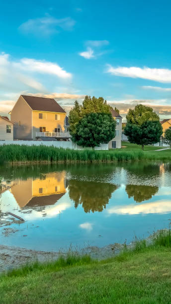 istock Vertical Homes trees and cloudy blue sky reflected on the mirror like surface of a pond 1170228166