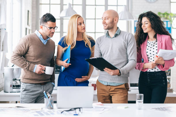 istock Team standing in modern office, discussing, pregnant woman 1170228709