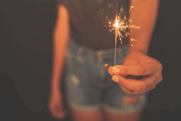 young girl burning sparkler in hand in the dark