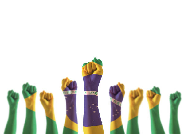 노동절 국경일 축하를 위해 주먹을 쥐고 있는 사람들의 손에 브라질 국기를 들고 하얀 배경에 고립된 브라질 권력을 강하게 유지한다(클리핑 경로) - 독립 뉴스 사진 이미지