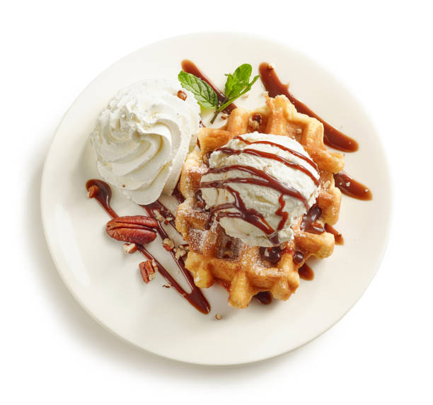 plate of belgian waffle dessert decorated with ice cream and chocolate sauce isolated on white background, top view