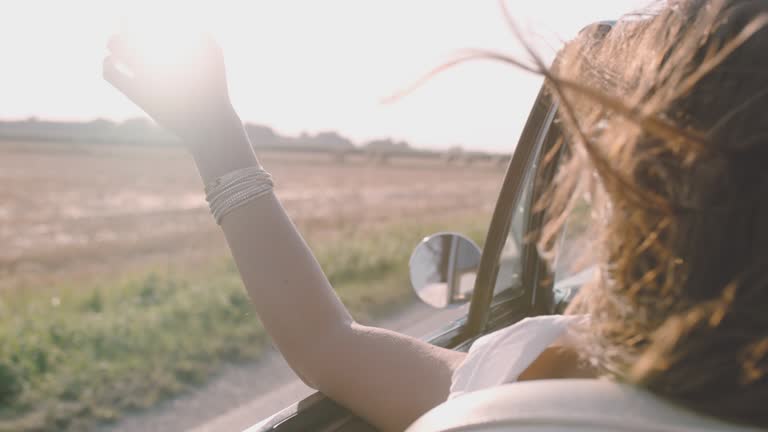 SLO MO Carefree young woman driving convertible along sunny, rural field