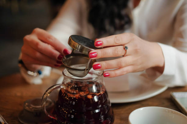 Office worker on lunch. young woman drinking tea in the restaurant. closeup of hands holding a pot of tea in a cafe.