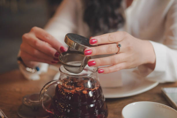 Office worker on lunch. young woman drinking tea in the restaurant. closeup of hands holding a pot of tea in a cafe.
