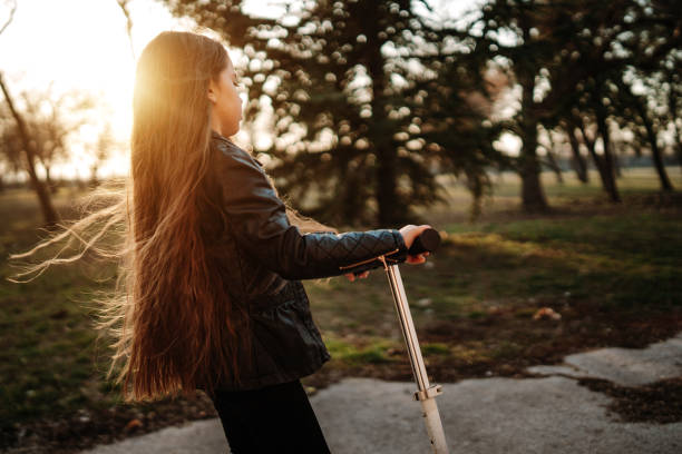 istock Cute girl riding scooter in park 1170247206