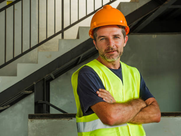 istock blue collar construction worker. Corporate portrait of young attractive and happy builder man or constructor posing confident smiling wearing building helmet and vest in blue collar job lifestyle 1170247238