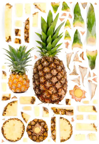 Large collection of pineapple fruit pieces, slices and leaves isolated on white background. Top view. Seamless abstract pattern.