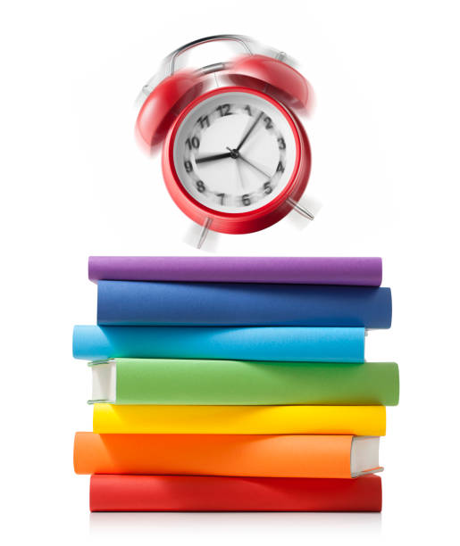 Alarm clock ringing on stack of colored books on white background