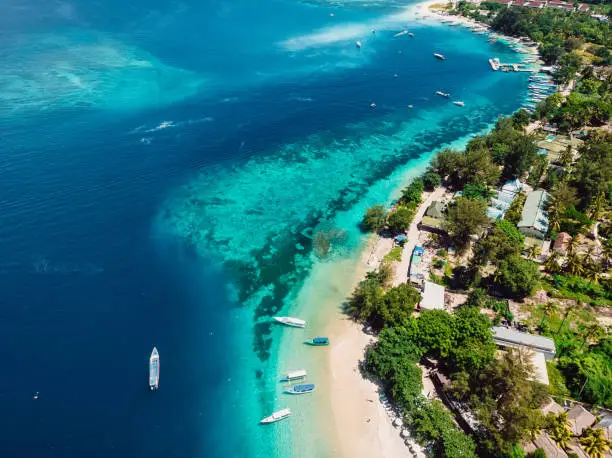 Tropical island with beach, boats and turquoise crystal ocean, aerial view. Gili islands